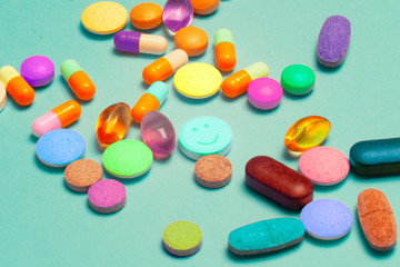Pills on a blue background. Assorted pharmaceutical medicine pills, tablets and capsules, health macro. Heap of various pills on color background. LSD pills drugs, bright Psychedelic pill.