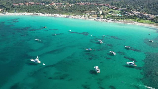 View from above, stunning aerial view of some boats and luxury yachts floating on a beautiful turquoise clear water. Golfo di Marinella, Sardinia, Italy.