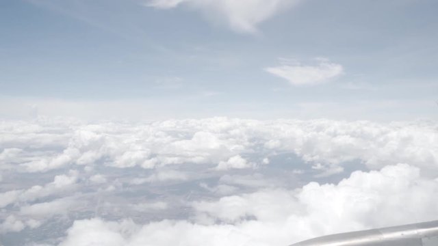 4K dolly in and out from the inside of a flying plane to the window to see the blue sky and white clouds