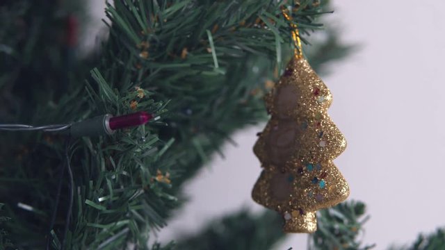 Golden bax christmas ornament hanging on dry tree branch. 4K handheld shooting.