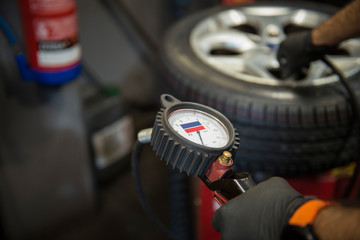 Man using the manometer to inflate a new tire in the garage
