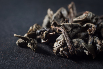 large leaves of dried green tea in a compressed state on a dark background