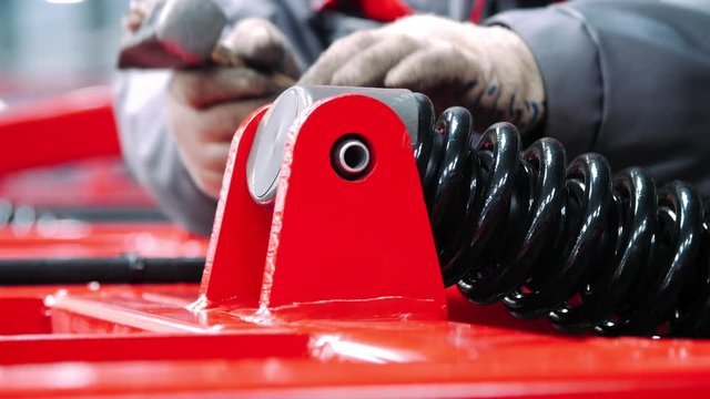 Mechanic working in assembly workshop heavy units. Fastening of shock absorber