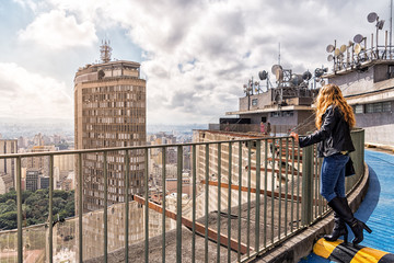 Blond Brazilian Woman Looking at the São Paulo City Skyline from the Roof of COPAN, during...