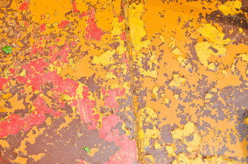 Texture of iron metal painted multicolored red yellow peeling paint of old battered scratched cracked ancient rusty metal sheet wall with corrosion. The background