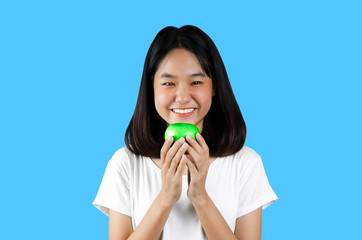 A young girl holding a green apple with the blue background