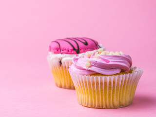 Two cupcakes with fruit filling on pink background.