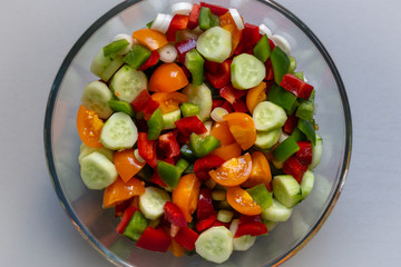 A glass bowl full of chopped vegetables view from above.