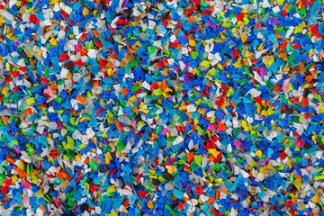 Crushed plastic granules for recycling.  Plastic crusher. Recycled plastic with mixed colors. The...