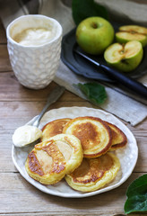 Homemade apple fritters with sour cream, coffee and green apples on a wooden background. Rustic style.