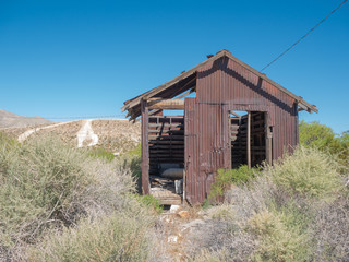 An historic dilapidated tin building and dirt bike motor sport track in the background in Goodsprings, Nevada, USA.