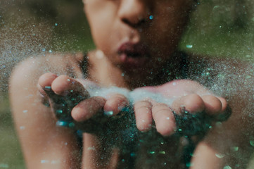 A young african american blowing sparkly confetti in the air