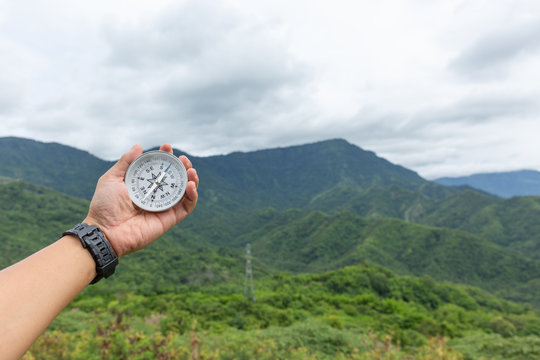 hand holding compass with mountain background, travel concept.