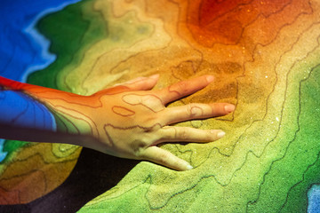 Girl hand touch on sand with colorful light from projector shining to hand