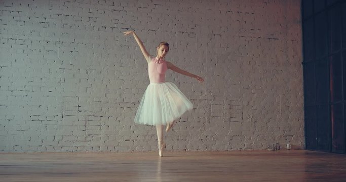 Young ballerina rehearsing in the hall. Beautiful girl dancing on pointe.