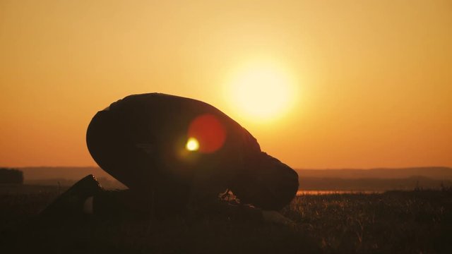 Silhouette young man praying outside at beautiful sunset. Male asks for help finding solace in faith, concept religion.