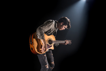 Guitarist, music. A young man plays an acoustic guitar on a black isolated background