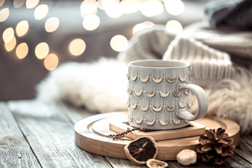 Coffee cup over Christmas lights bokeh in home on wooden table with sweater on a background and...