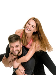Portrait of cheerful athletic man carrying his laughing woman on back