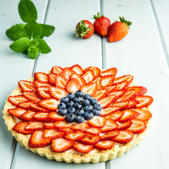 Cake with berries Pie with strawberries and blueberries on blue rustic table.