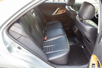 View to the interior of car with dashboard, rear seats, black leather after cleaning before sale on parking
