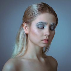 The face of a young woman with delicate face art in the winter style. Conceptual female makeup.
