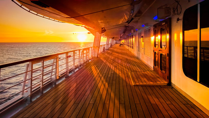 Pont promenade d'un navire de croisière en navigation avec coucher de soleil.