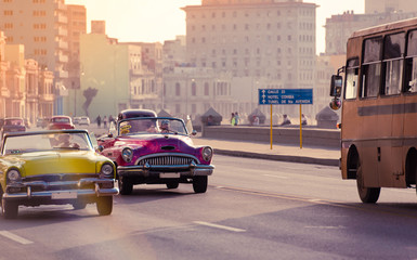 Gelber und pink farbener Cabriolet Oldtimer fahren auf der Promenade el Malecon in Havanna Stadt...