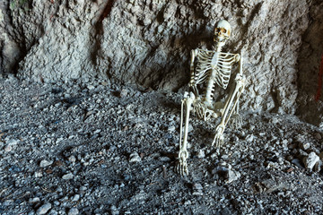 Skeleton in a dark cave in the ground lying on rocks