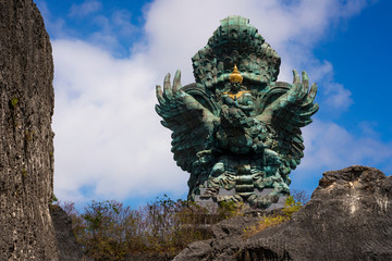impressive view of Garuda Wisnu green copper statue inspired in Hindu myth standing majestic under...