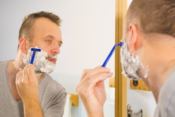 Guy shaving his beard in bathroom