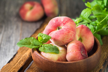 Fig peach in a wooden bowl. Flat peach