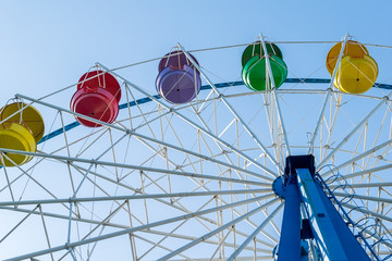 ferris wheel from the amusement Park with colorful baskets of seats against the blue sky
