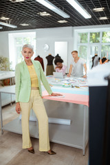 Beautiful elderly fashion designer standing in a workshop