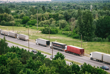 Queue of trucks passing the international border, red and different colors trucks in traffic jam on the road.