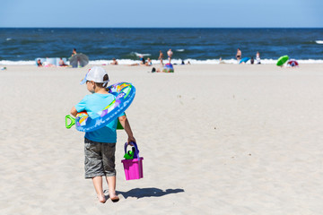 Cute boy with beach toys on tropical beach