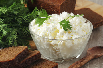 A bowl with cottage cheese, a bunch of green and rye bread