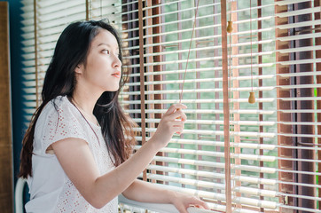 The beautiful woman standing near window indoor in the  mornings are very pleasant