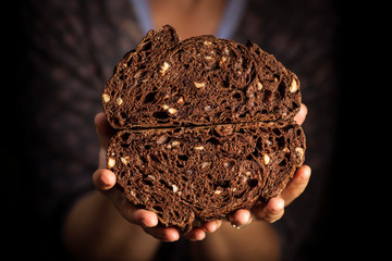 Woman holding in her hands a home made black bread from chocolate and nuts