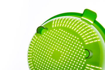 Close-up of a green plastic colander, a kitchen utensil to drain pasta, on a white background. Photo with copy space.