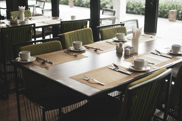 Empty restaurant part of hotel with table and armchair near windows.
