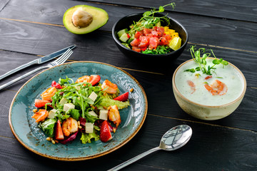 lunch in a Thai restaurant, three dishes on the table soup with seafood, salad and fresh fish.