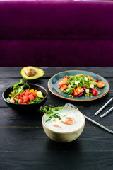 lunch in a Thai restaurant, three dishes on the table soup with seafood, salad and fresh fish.