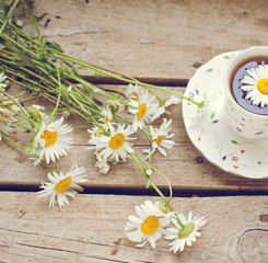 Fototapeta na wymiar cup tea with chamomile flowers on wooden table