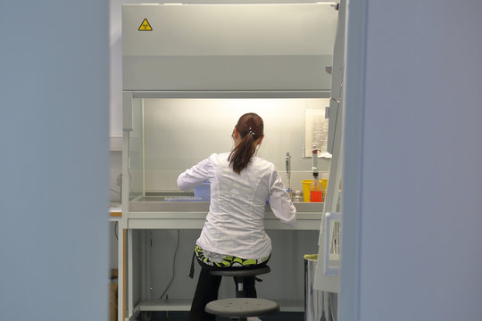 Young nurse in white uniform sitting in chemical laboratory