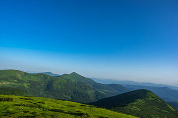 Fototapeta premium Green hills against the blue sky in the mountains