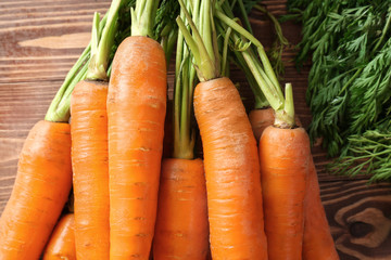 Tasty fresh carrot on wooden background, closeup