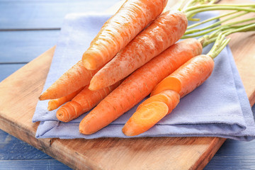 Tasty fresh carrot on wooden board, closeup