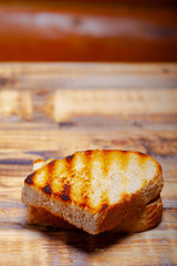 Grilled bread on burned wooden table. Preparing for traditional rural dinner