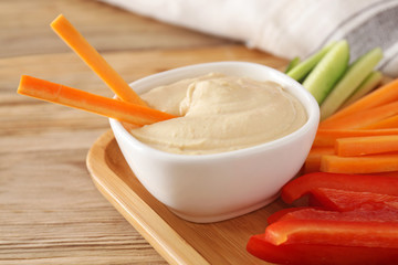 Bowl of tasty sauce and fresh vegetables on wooden table